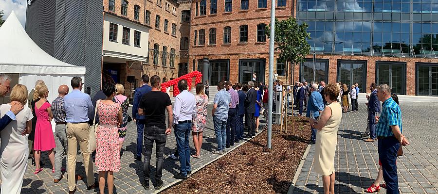 Na zdjęciu: Ludzie stoją i obserwują uroczyste otwarcie biurowca w danej fabryce Stoewera, wspartego ze środków Jessica II